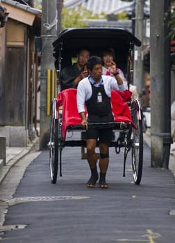 KYOTO , JAPAN - OCT 24 : Japanese couple on a trditional rickshaw being pulled by a man on October 24 2009 in Kyoto , Japan