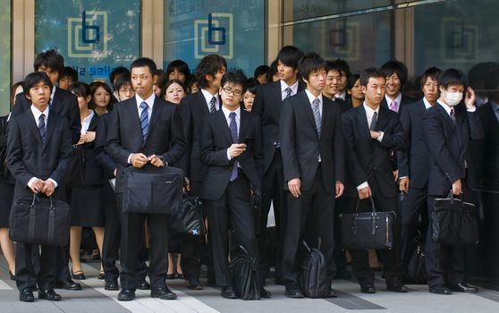 TOKYO - OCT 29 : Japanese office workers stands outside an office building in Tokyo Japan financial district on October 29 2009 