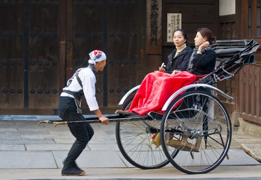 TOKYO - OCT 29 : Two Japanese women on a trditional rickshaw being pulled by a man on October 29 2009 in Tokyo , Japan