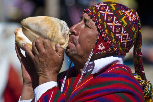 CHINCHERO , PERU - MAY 29 2011 : An unidentified Peruvian man with traditional clothes blowing a shell on May 27 2011 in Chinchero Peru , shell blowing is traditional in Peru