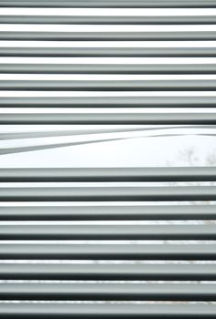 Peeking through the slats of venetian blinds.