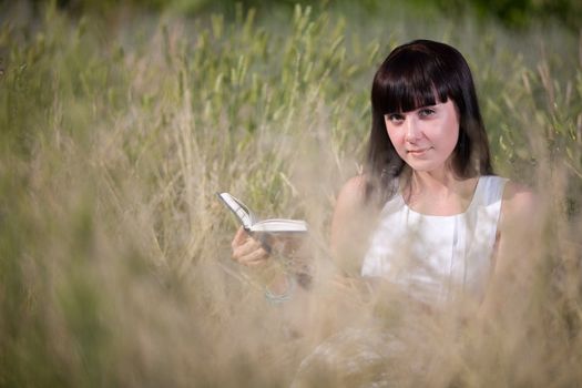 girl reading a book in the grass