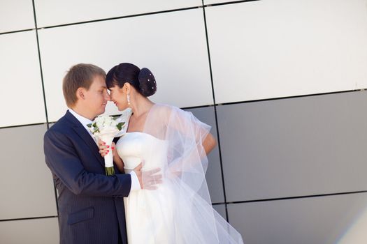 bride and groom by the wall