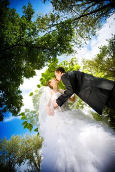 bride and groom kissing in the park