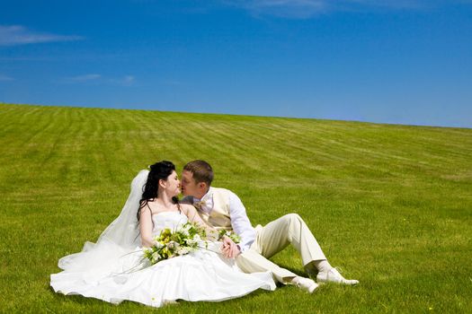 bride and groom kissing on the green grass