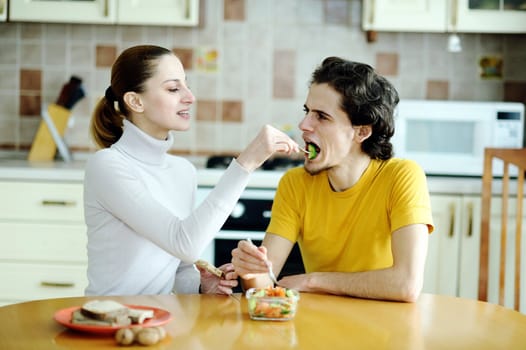 An image of young happy couple eating at kitchen