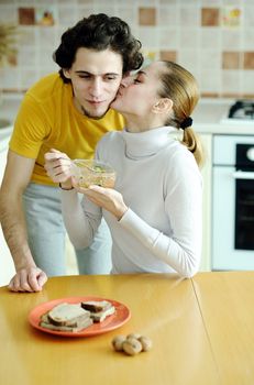 An image of young happy couple eating at kitchen