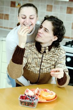 Funny scene of young happy couple playfully eating at kitchen