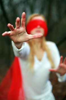 An image of young woman with red blindfold in a forest