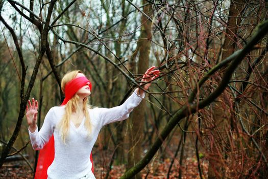An image of young woman with red blindfold in a forest