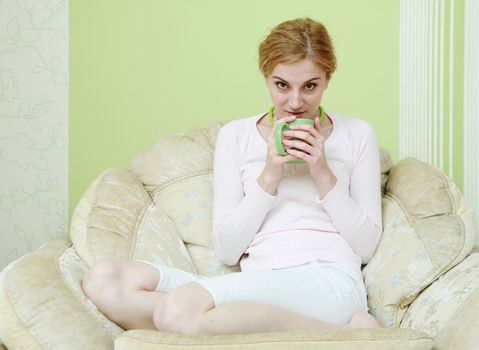 A woman drinking tea in the armchair