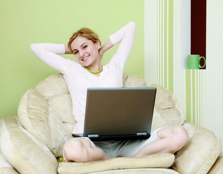 An image of woman with a laptop in armchair