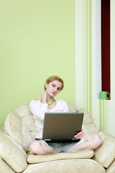 An image of a woman with a laptop in armchair