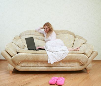 An image of a girl with a laptop on a sofa