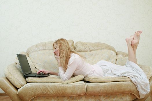 An image of nice girl with laptop on a sofa