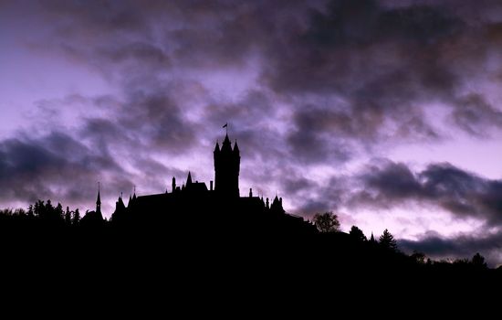 silhouette of the castle on hill over cloudy sky