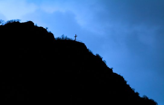blacj silhouette of the cross on the hill over dark blue sky