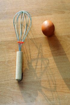 An image of an egg and a whisk on the table