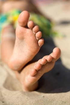 An image of little girl's feet on the sand