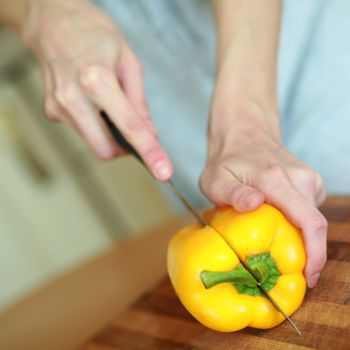 An image of hands cutting fresh yellow paprika