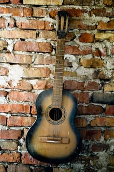 an old guitar on the brick wall