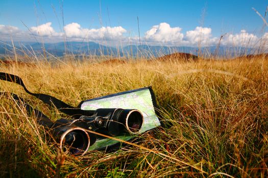 An image of binoculars and map on grass