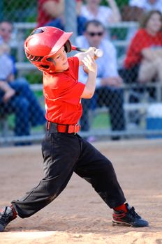 Little league baseball player full swing at bat