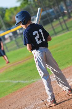 Youth baseball player waiting to bat at home plate.