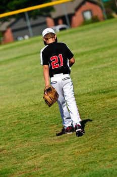 Youth baseball player walking onto the field to get ready to play.