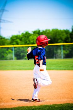 Youth little league player running bases.