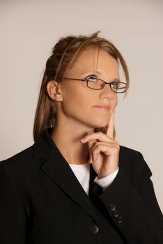 Business woman thinking wearing glasses and black suit in studio.