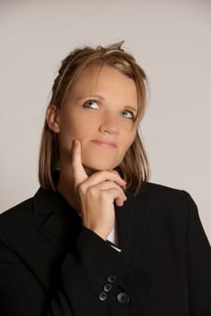 Beautiful business woman in a black suit thinking and looking up.