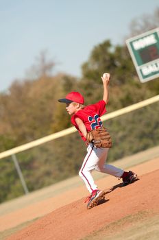 Young baseball player pitching the ball.