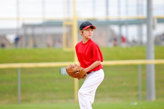 Little league baseball pitcher on the mound wearing a red jersey.