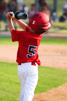 Little league player warming  up to bat.