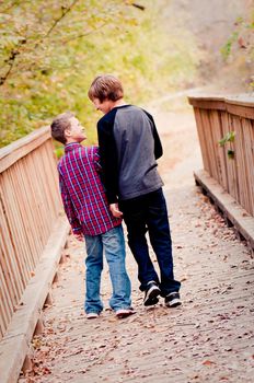 Two cute boys looking at each other on a bridge and smiling.