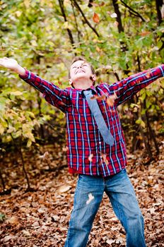 Young cute boy looking up with leaves falling down.