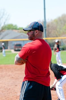 Baseball coach at first base line looking at batter.