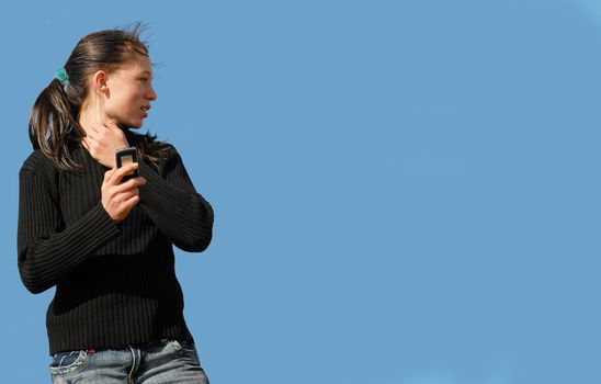 young teenager and her phone in a blue sky