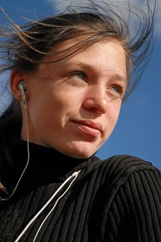 young teen listen her music in a blue sky