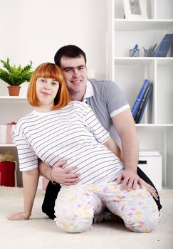 portrait of a husband and a pregnant wife at home with