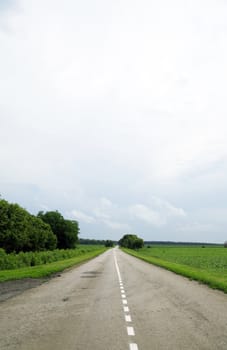 Empty asphalt road leaving on horizon against the blue sky