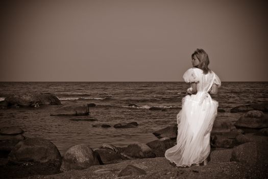 lonely woman in white dress looking to the sea 