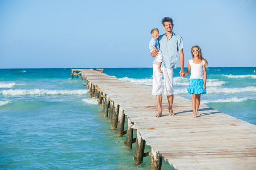 Family of three on wooden jetty by the ocean
