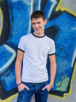 Young smile man in front of blue graffiti. Vertical view