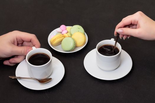 Couple drinking coffee with macaroon, on black