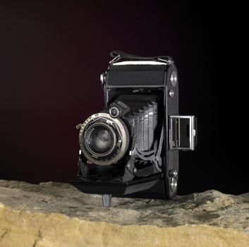 Still life with nostalgic camera on stone ground in front of dark back