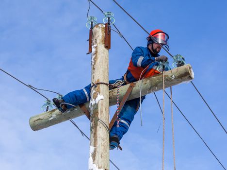 Electrician working at height without the aid of vehicles  against the blue sky