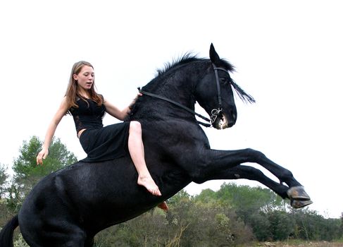 rearing black stallion and young woman in a field