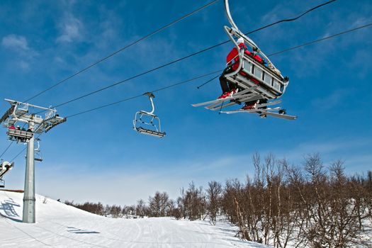 Chair skilift with skiers in bright winter day